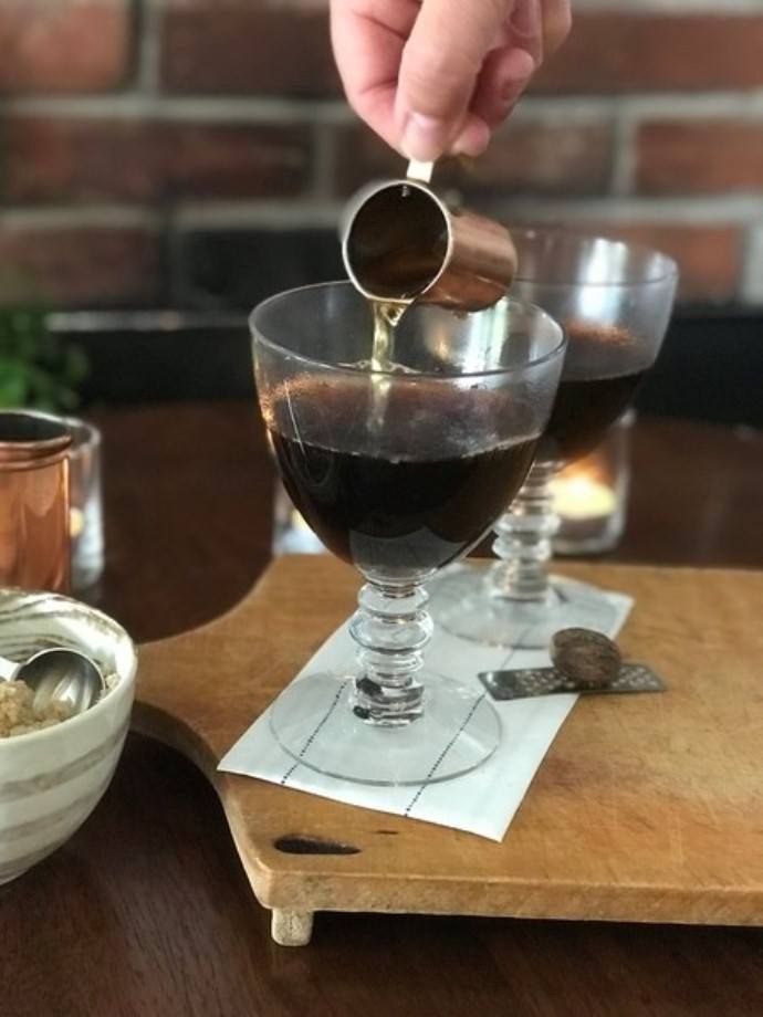 pouring whiskey into a glass with coffee