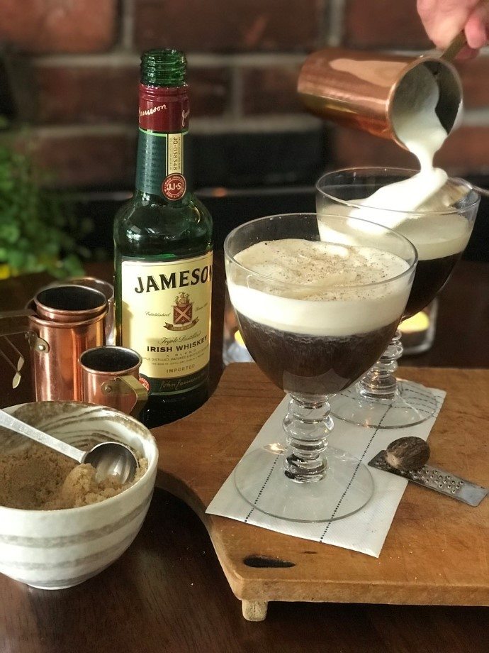 pouring fresh cream onto an Irish coffee glasses
