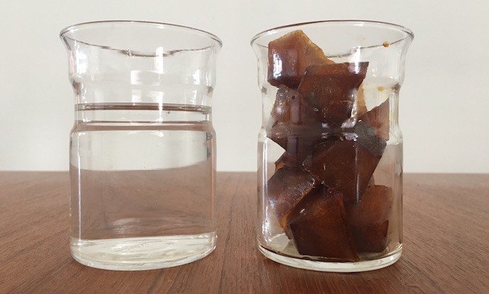 two glasses on a table and one is filled with cold brew coffee ice cubes