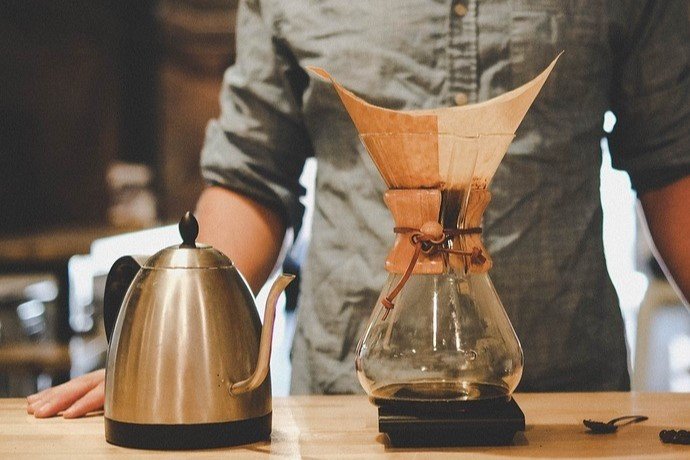 kettle for making hot water, chemex carafe, and coffee filter in front of a guy