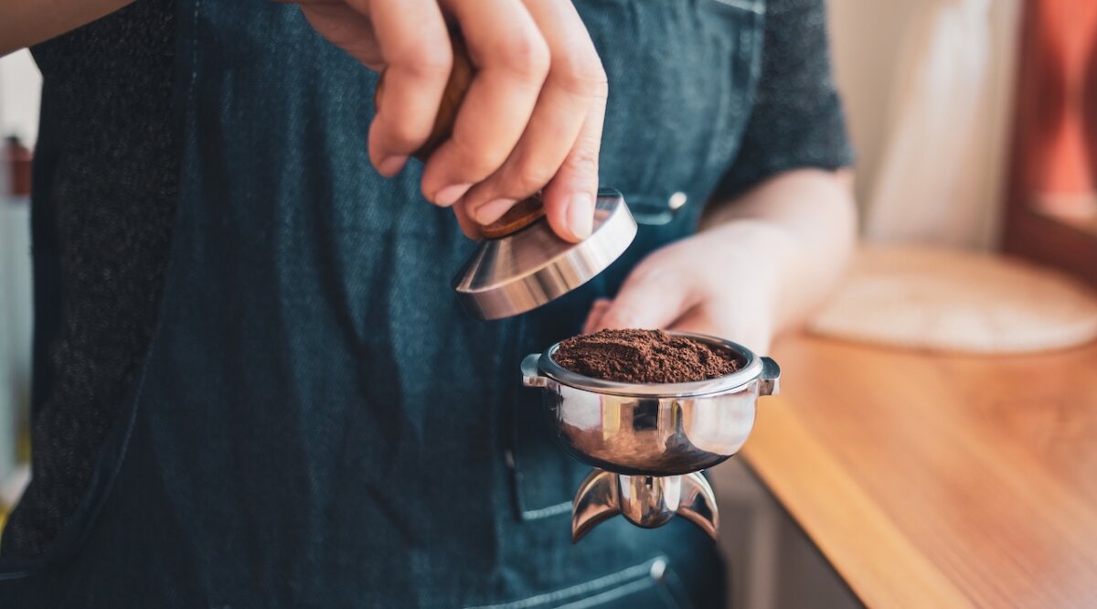 en person som stampar espresso