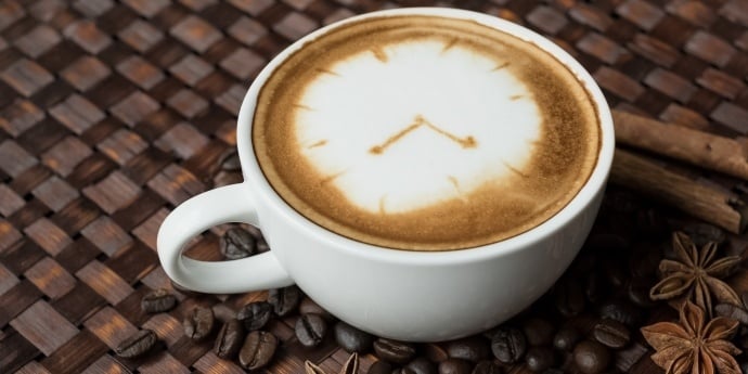 a cup of latte with a clock as art - clearly not a clean cup of coffee
