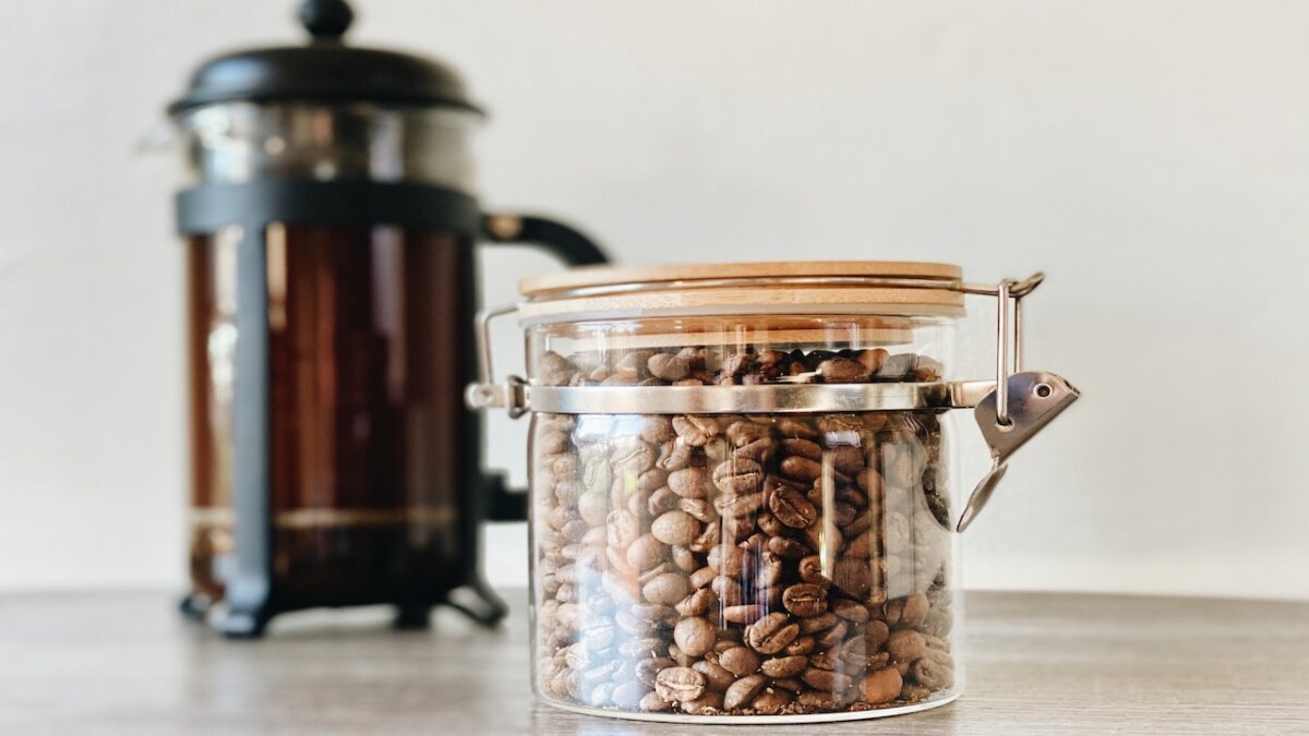 granos de café en un frasco y prensa francesa