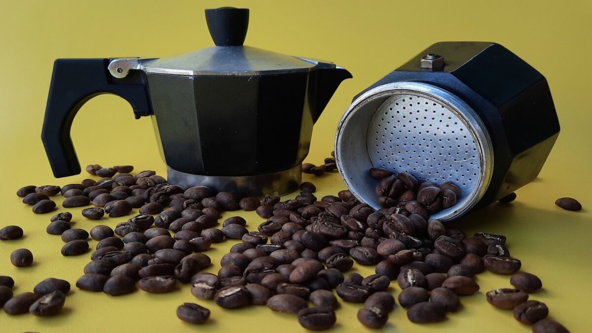 granos de café derramados junto a una olla mok