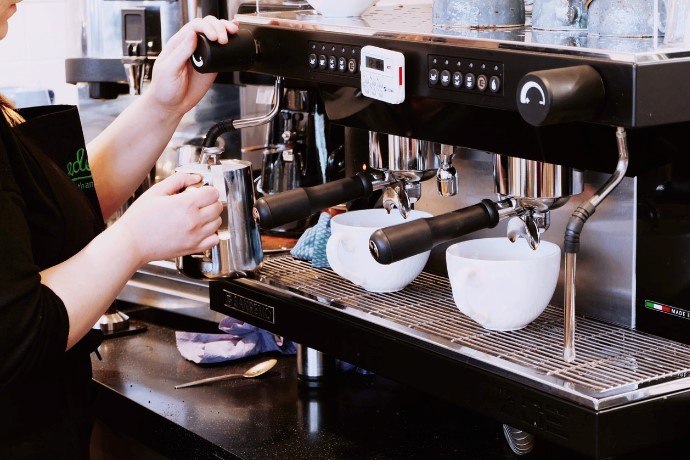 a barista steaming milk using a commercial espresso machine