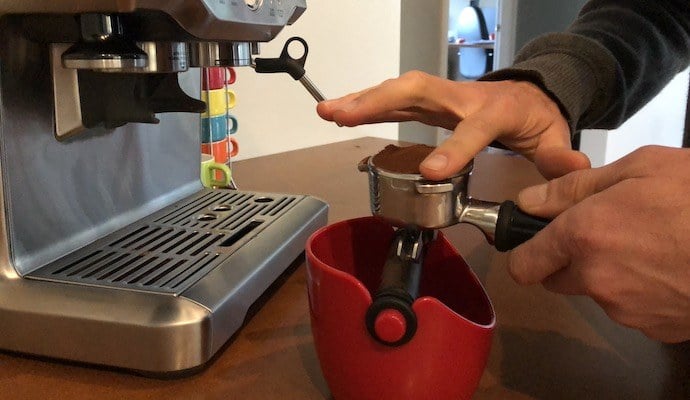 a barista smoothing excess coffee off the portafilter