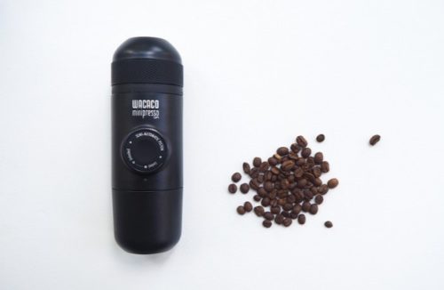 En bärbar espressobryggare av märket Wacaco minipresso och en hög med kaffebönor