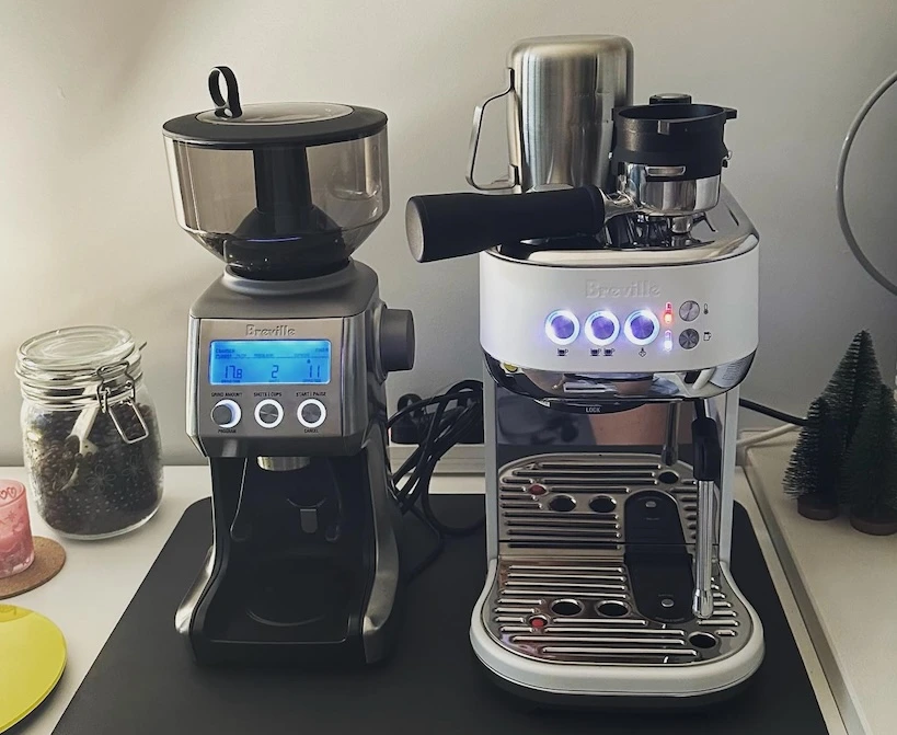 Breville smart pro grinder next to a white Breville espresso machine on the kitchen counter.