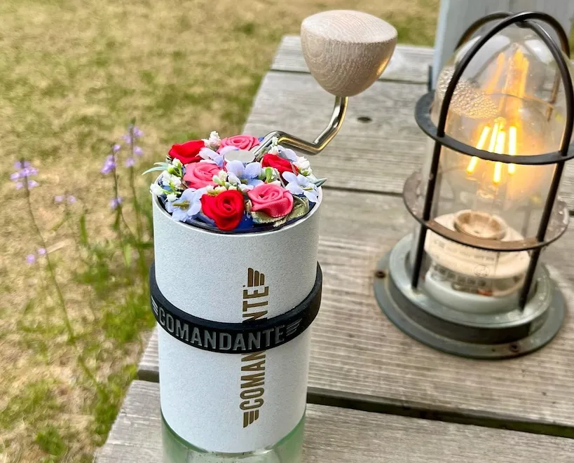 white comandante grinder with flowers in it instead of coffee beans