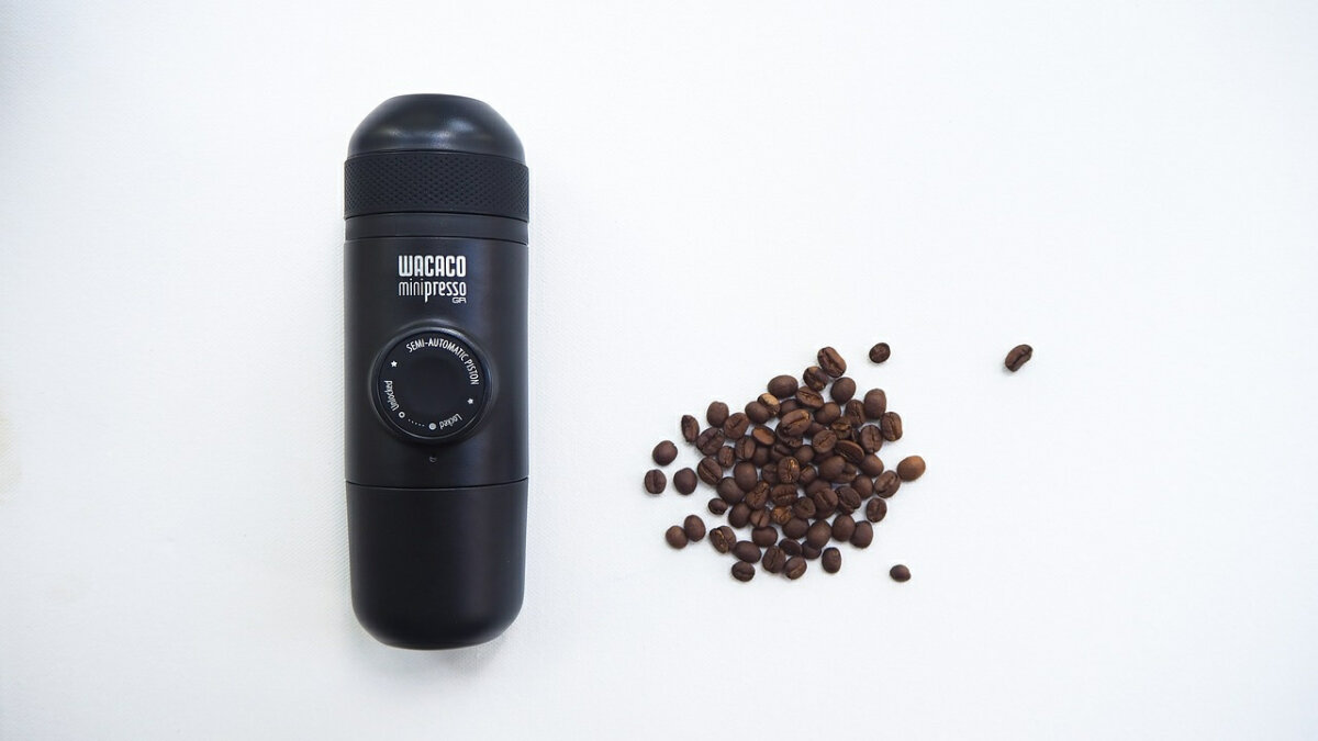 wacaco bärbar espressomaskin bredvid kaffebönor