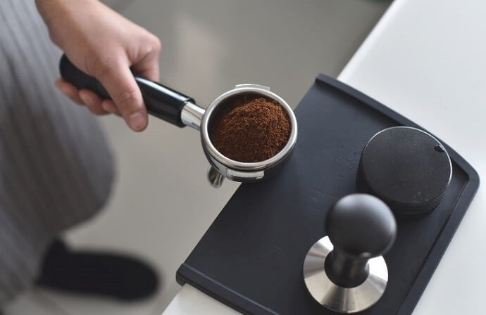 espro calibrated tamper review - a portafilter filled with espresso grounds, a tamper
