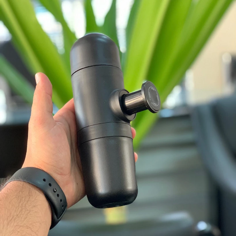 Person holding Wacaco Minipresso in front of plant
