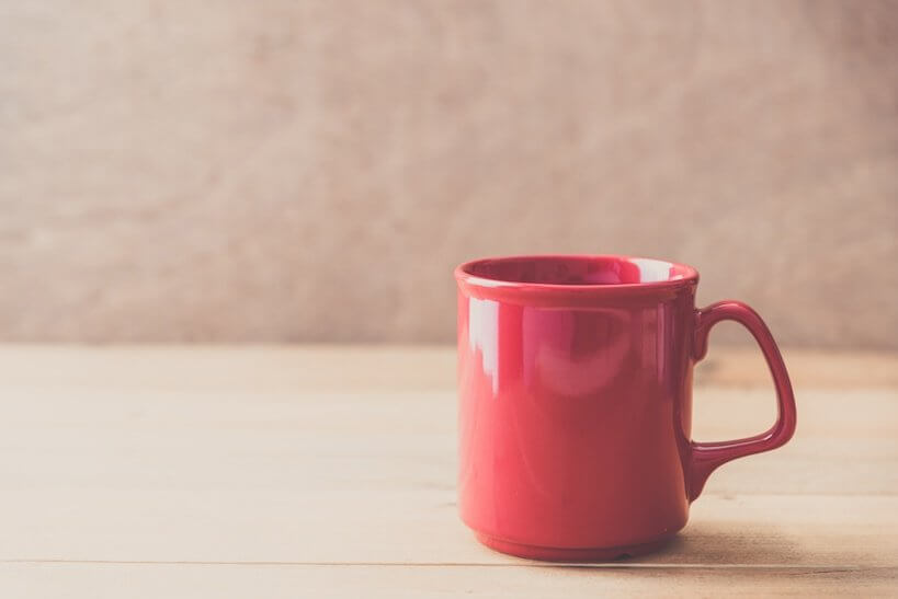 red coffee mug on a light brown colour table