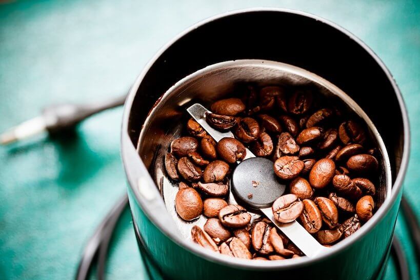 coffee beans in a green grinder