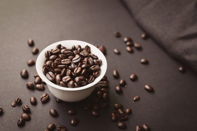 coffee beans in a mini white bowl on a table