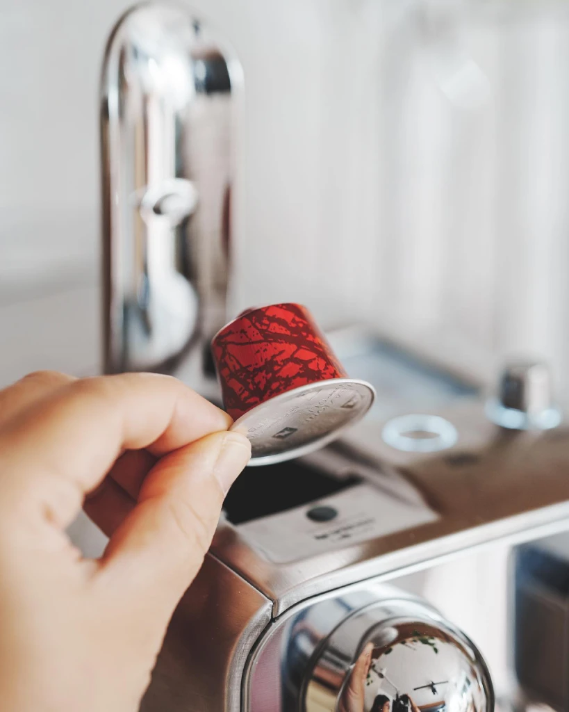 person holding coffee capsule with pod machine