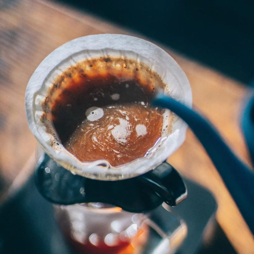 Adding water to pour over coffee maker with paper filter