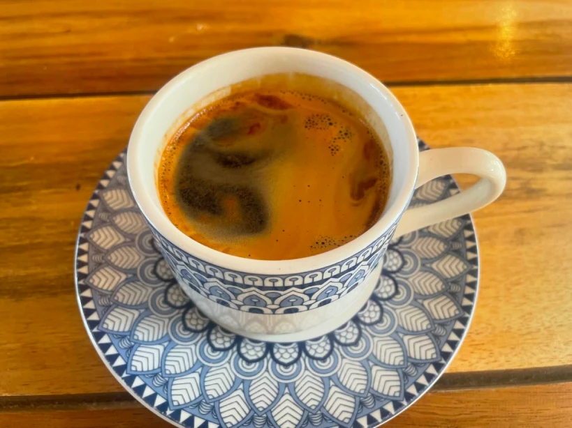 Black coffee in blue patterned cup and saucer