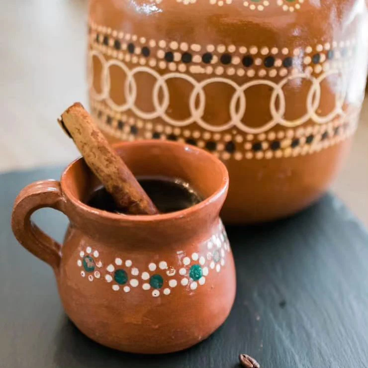 Cafe de olla in traditional clay cup with pot