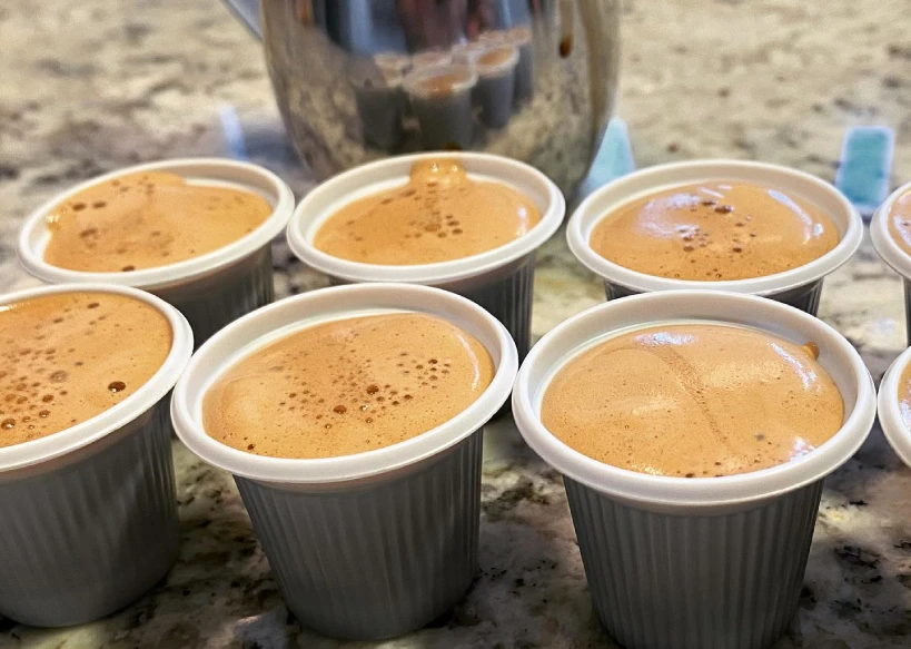 Small plastic cups of Cuban coffee with metal jug