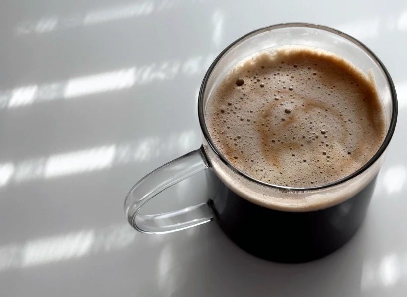 Black coffee in glass cup under shadow