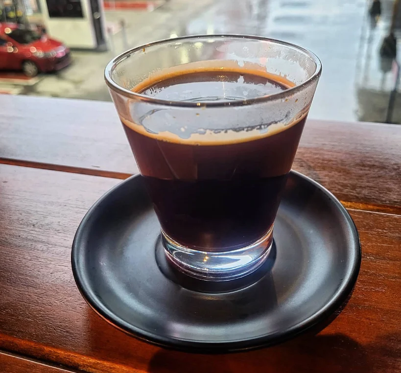 Red eye coffee in glass cup on windowsill